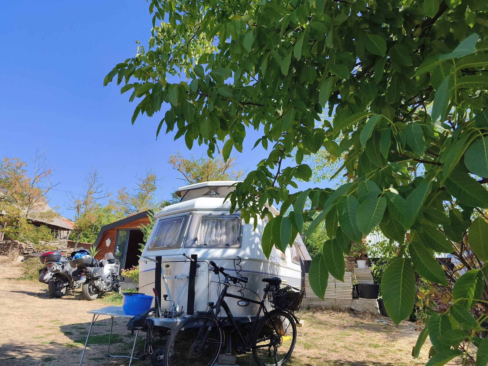 Motorcycles and a campervan parked at Teddy Camp, TET Trans Euro Trail rider stopover Kosovo
